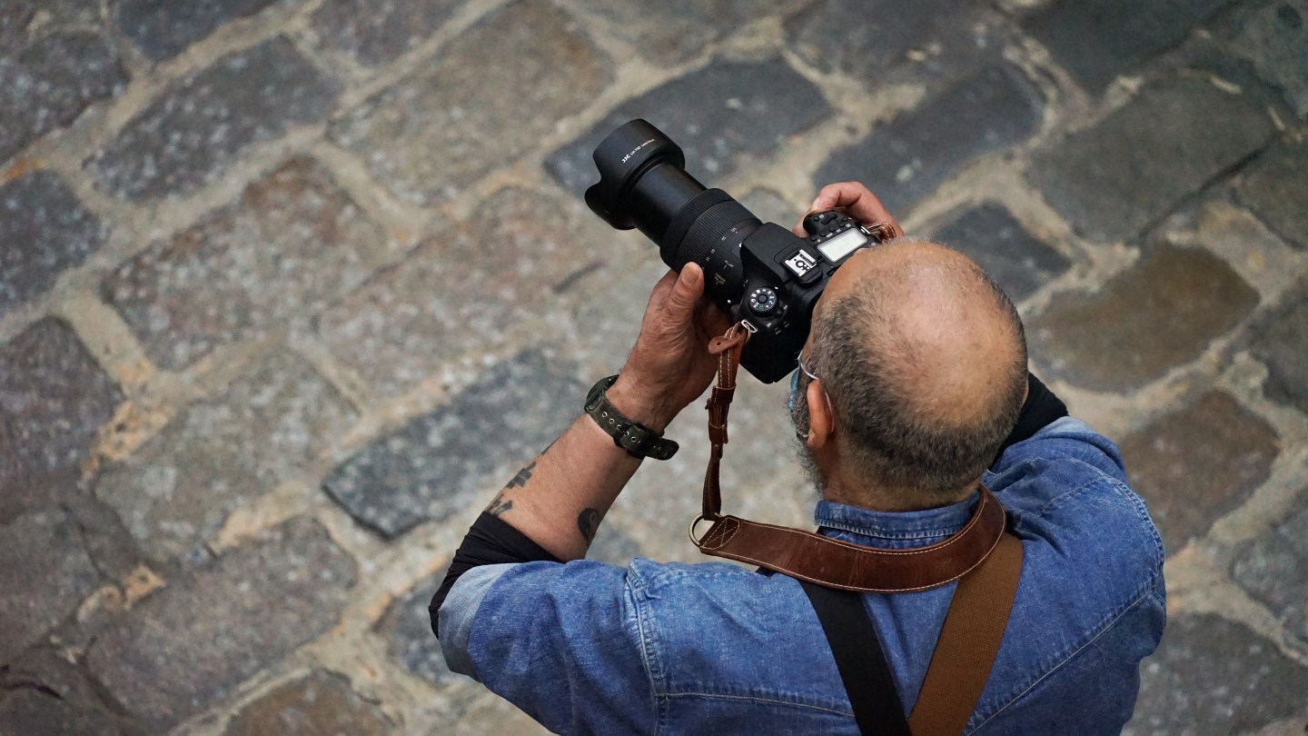 Photographe utilisant un téléobjectif dans la rue, vu de dessus