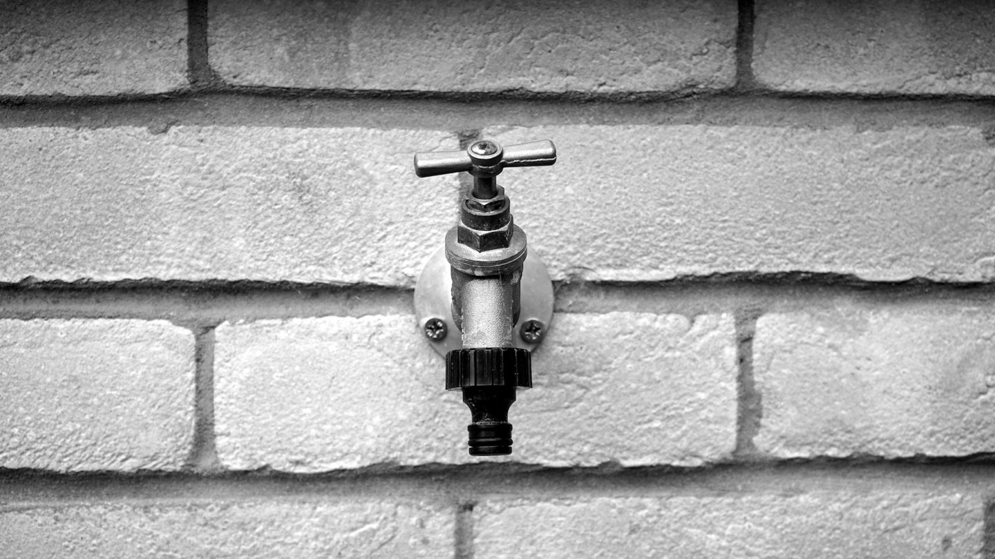 Robinet ancien sur un mur de briques en noir et blanc