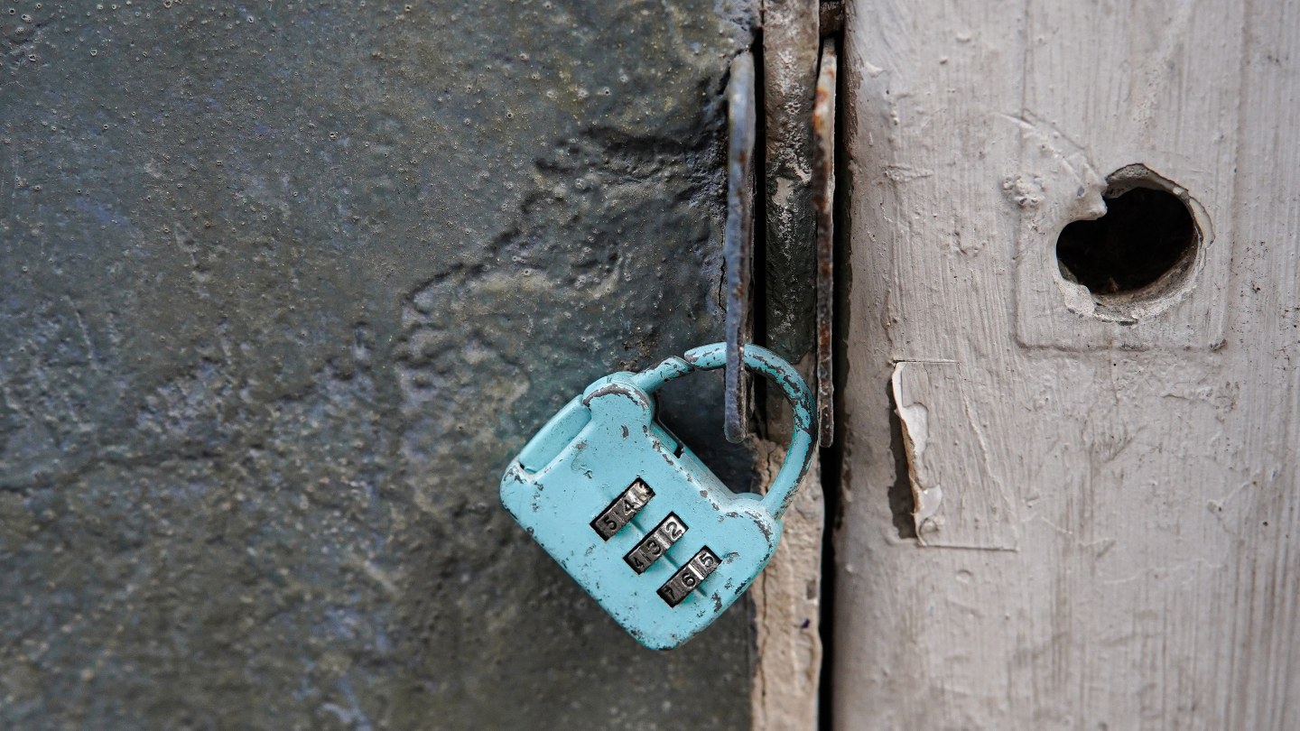 Cadenas &agrave; code turquoise accroch&eacute; au loquet d'une vieille porte